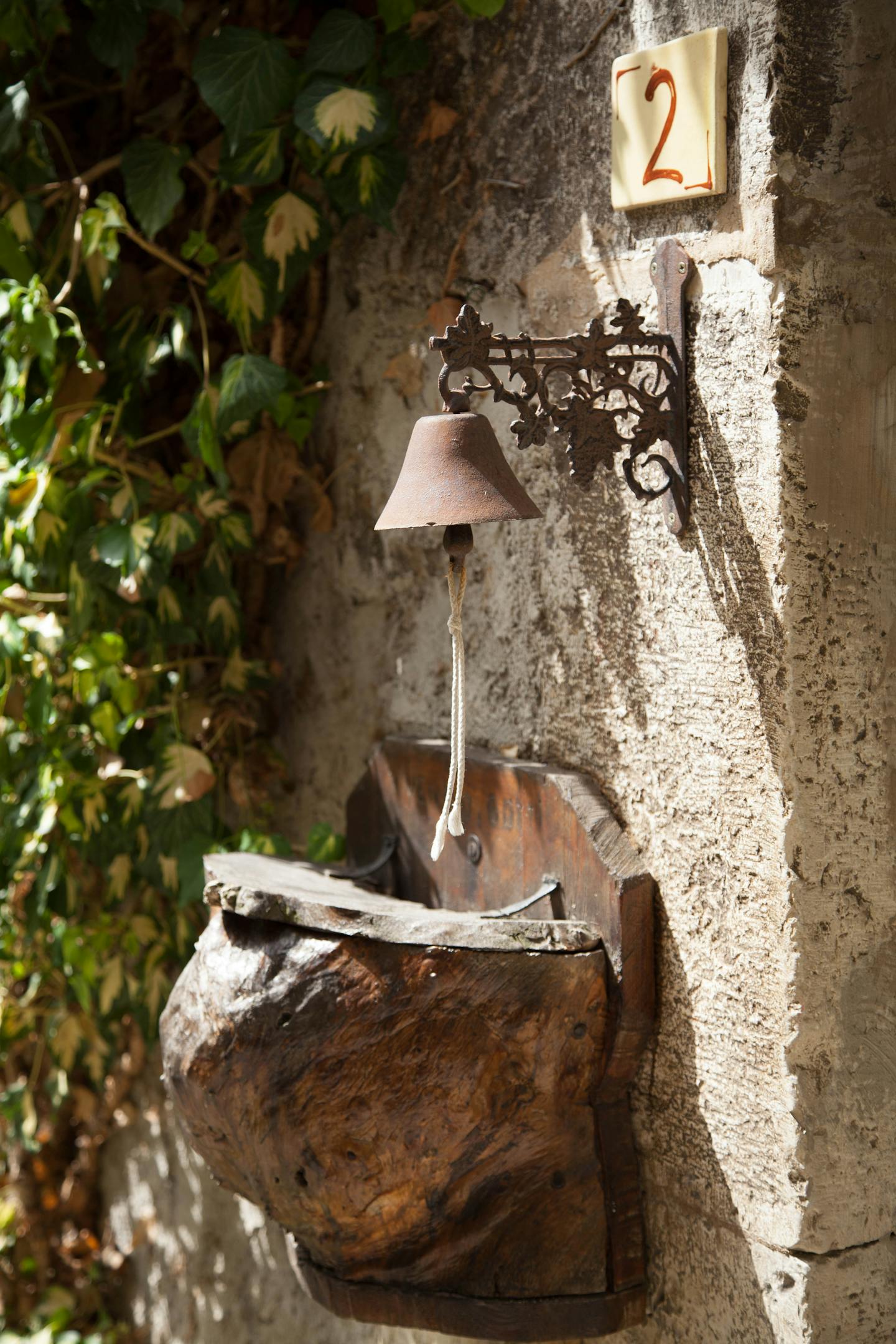 Close-up of antique bell with ivy and number 2 on a rustic wall in Die, France.