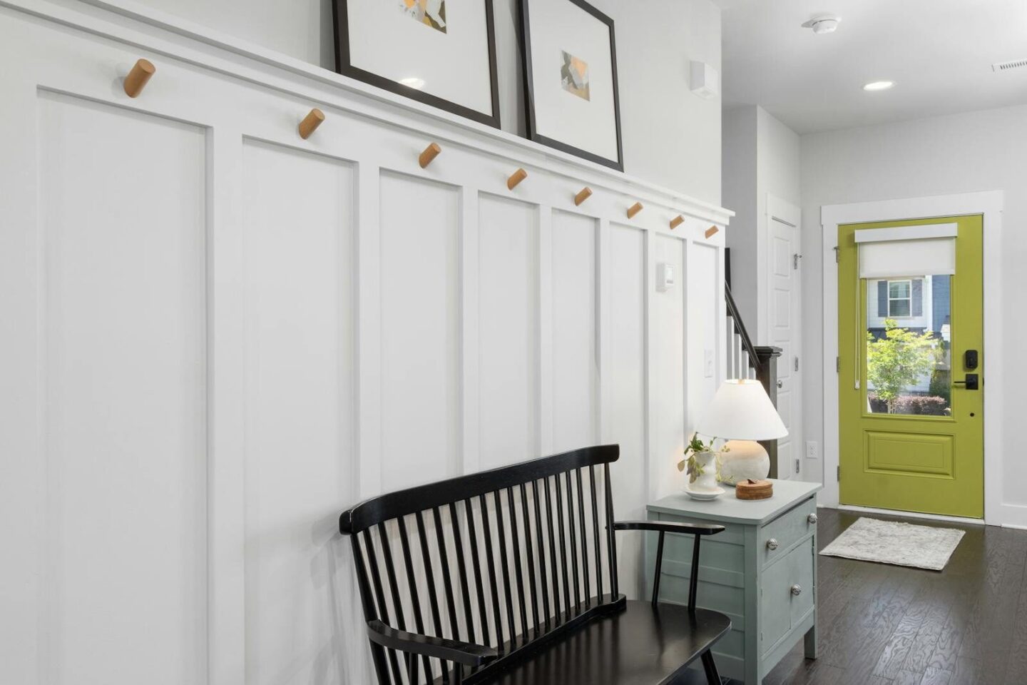 Stylish entryway featuring a green door, black bench, and decorative elements.